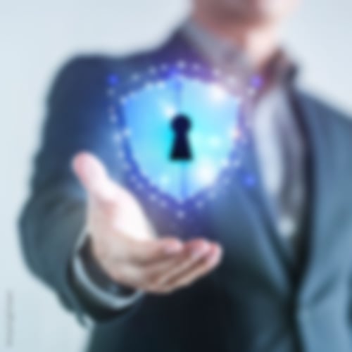 Mann hält ein virtuelles Schutzschild mit Schlüsselloch in der Hand als Zeichen für Datensicherheit und Datenschutz