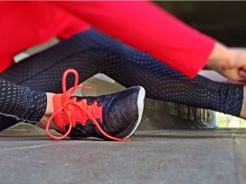 Eine Frau in Sportkleidung bindet sich die Schuhe zu