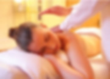 Eine Frau liegt auf dem Bauch auf einer Liege und wird von einem Therapeuten massiert