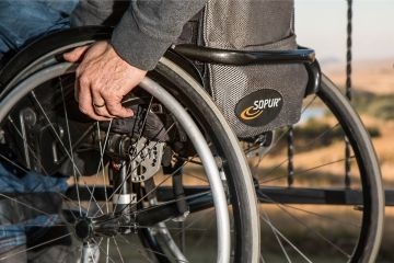 Ein Mann sitzt in einem Rollstuhl und umfasst ein Rad mit einer Hand