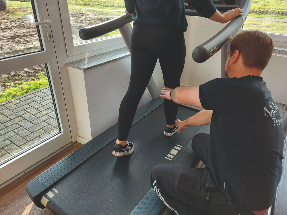 Physiotherapeut behandelt Patientin auf einem Laufband