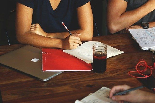 Gruppe sitzt am Tisch mit Unterlagen und Laptop