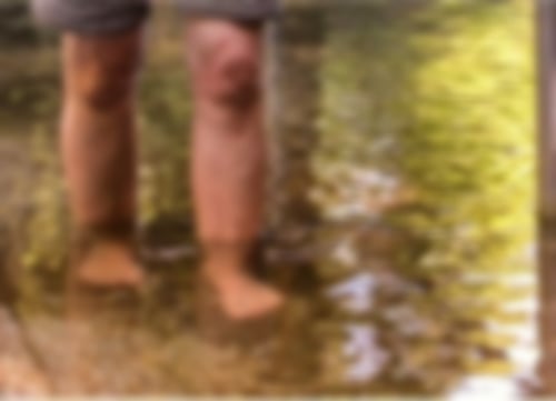 Ein Mann tritt barfuß in klares Wasser