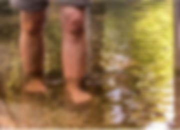 Ein Mann tritt barfuß in klares Wasser