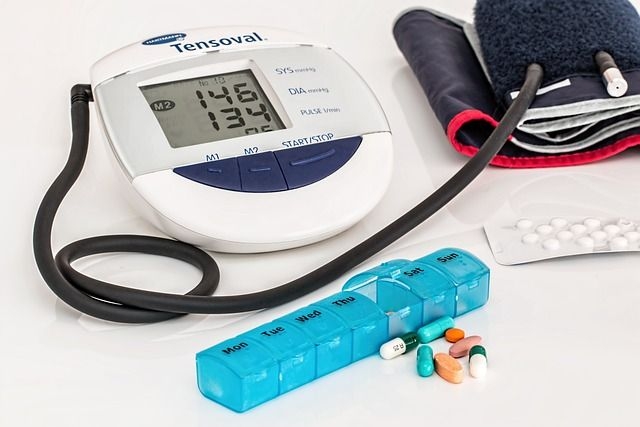 Ein Blutdruckmessgerät neben einer Packung Tabletten auf einem Tisch