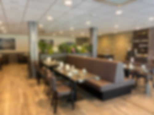 Auf einem weißen Teller liegt ein gebratenes Stück Lachs sowie ein gemischter Salat und ein Stück Zitrone.