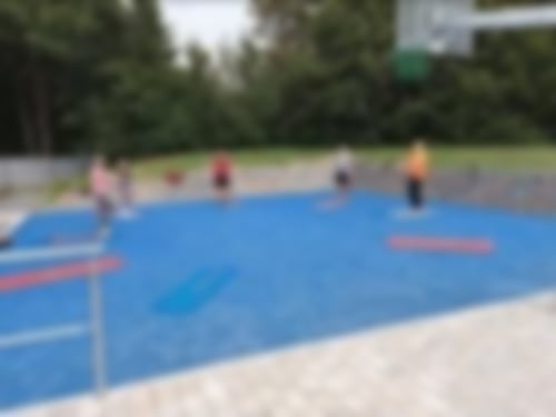 Auf unserem Outdoorplatz wird ein Fitnesskurs durchgeführt. Mehrere Patienten und eine Therapeutin haben sich auf ihren Matten in einem Kreis angeordnet.