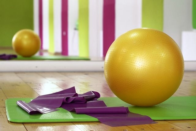 Ein Pezziball und ein Gymnastikband auf einer Trainingsmatte in einem Kursraum
