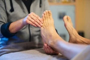 Eine Patientin bekommt eine Fußreflexmassage von einer Therapeutin.