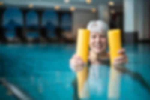 Eine Frau im Wasser mit einer gelben Wassernudel