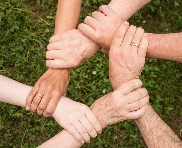 6 Hände bilden durch Anfassen einen Kreis als Symbol für Zusammenhalt und gegenseitige Unterstützung