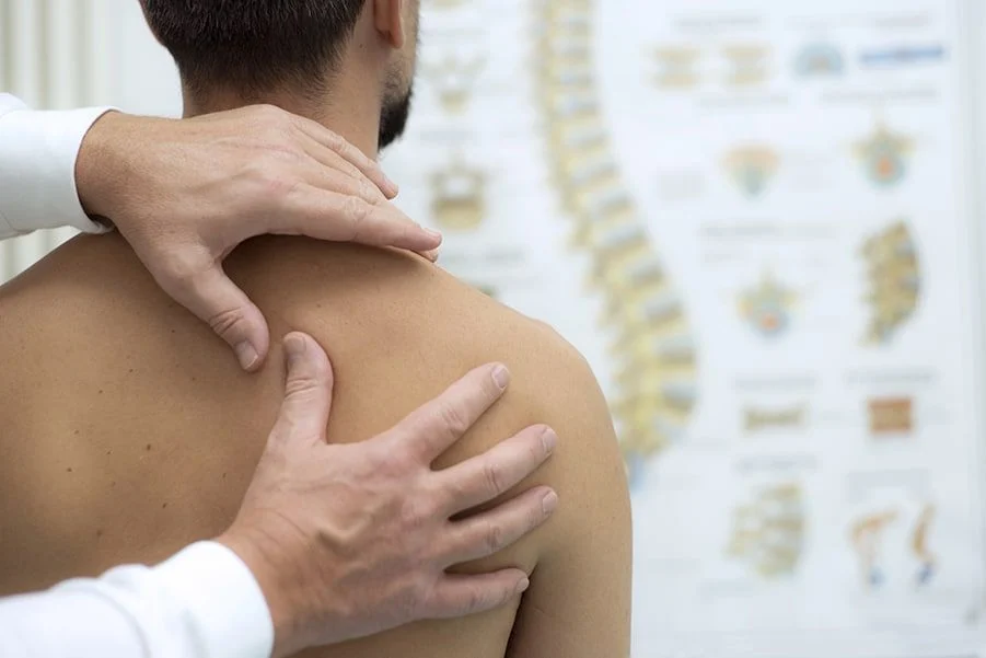 Ein Arzt untersucht die Schulter eines Patienten