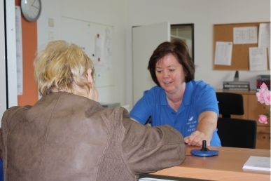 Eine Pflegerin erklärt einer Patienten an einem Tisch etwas