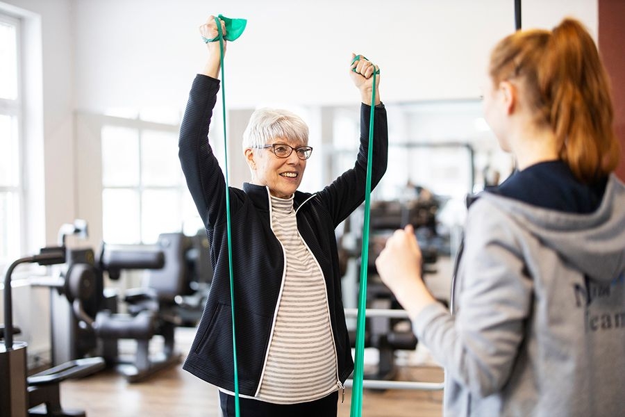 Sportlerin am Theraband mit Trainerin