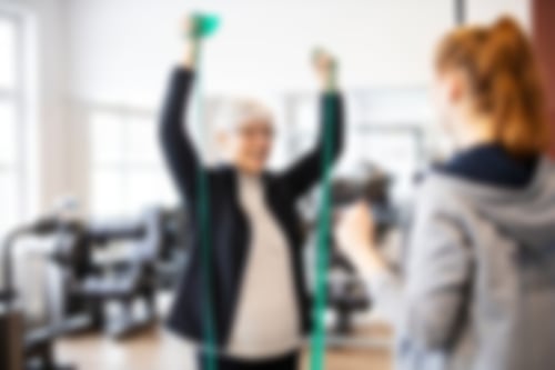 Sportlerin am Theraband mit Trainerin
