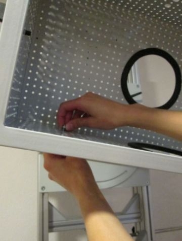 Eine Hand steckt eine Schraube in einen Montagekasten