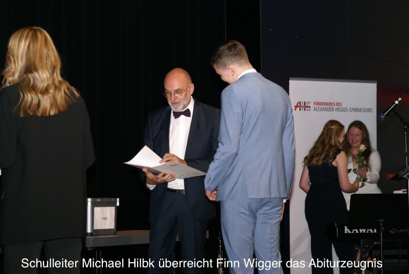 Schulleiter Michael Hilbk überreicht Finn Wigger das Abiturzeugnis