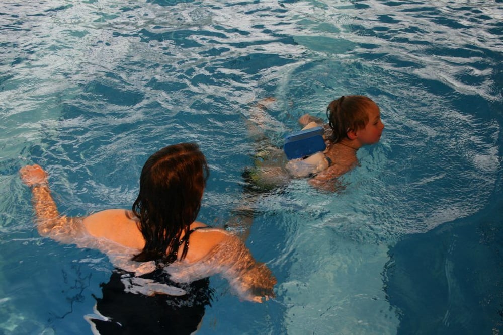 Kind mit Schwimmtrainerin im Wasser