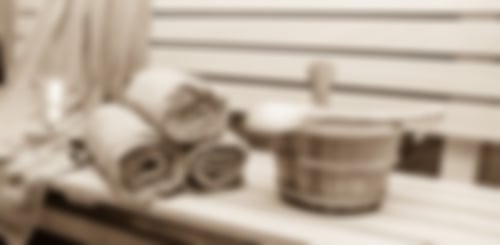 Saunatücher und Eimer stehen auf einer Saunabank