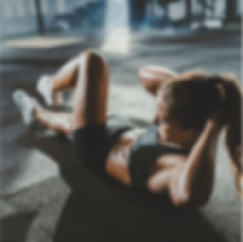 Eine Frau liegt mit dem Rücken auf dem Boden und führt eine Fitnessübung durch