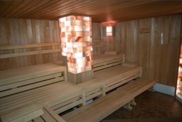 Innenansicht der Westernkötter Salzstein-Sauna, eine unserer 6 Saunen. Zu sehen sind die Bänke und die leuchtende Salzstein-Säule.