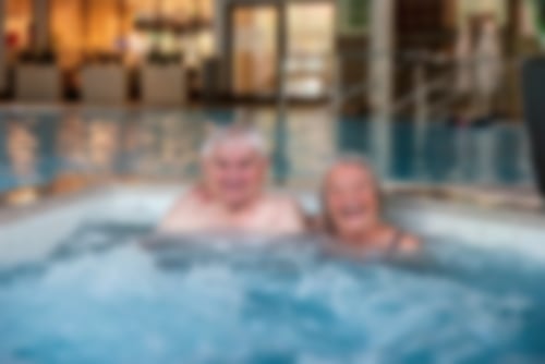 Ein Paar sitzt in einem unserer Whirlpools und lacht in die Kamera.