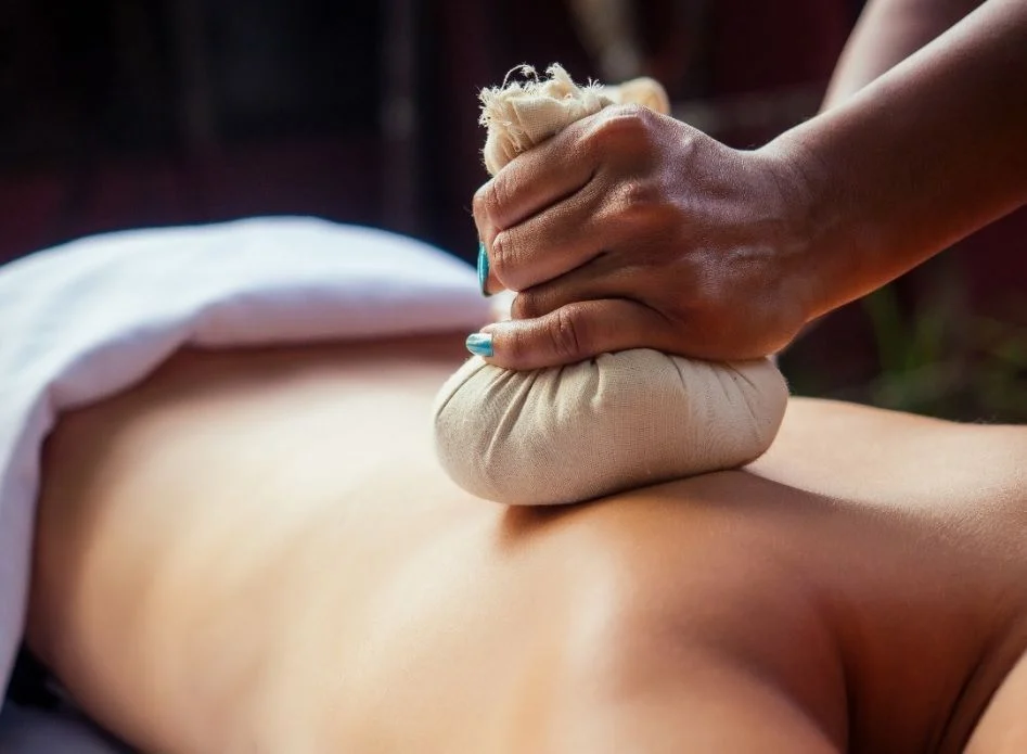 Massage mit einem Kräuterstempel