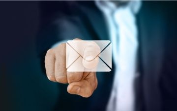 Symbolbild E-Mails. Ein Finger zeigt auf einen Brief.