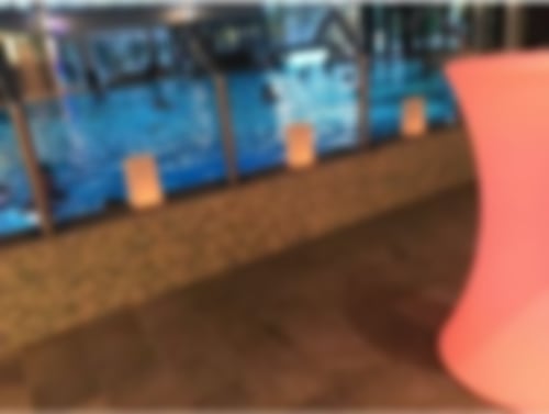 Wohlfühlatmosphäre in den Hellweg-Sole-Thermen. Im Vordergrund steht ein leicht rot leuchtender Tisch, am Beckenrand stehen Papiertüten mit Herzen drauf, innen brennen Kerzen. Im Schwimmbecken dahinter genießen die Gäste das wohltuende Solewasser.