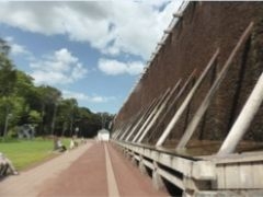 Das große Gradierwerk I im Kurpark von Bad Westernkotten. Auf der linken Seite stehen mehrere Bänke, auf denen sich Besucher entspannen.