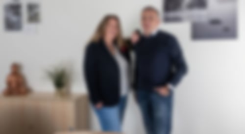 Simone Ruhnau, Fachfrau für Finanzen, und Finanzierungsspezialist Thorsten Stede stehen gemeinsam im Büro und lächeln in die Kamera