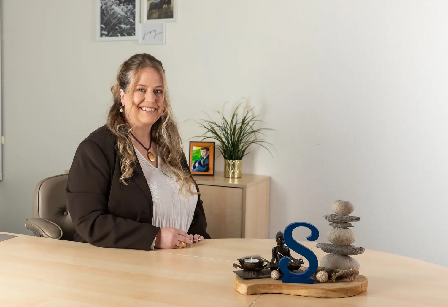 Simone Ruhnau, Fachfrau für Finanzen, sitzt an ihrem Schreibtisch im Büro und lächelt in die Kamera – unabhängige Finanz- und Versicherungsberatung