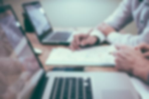zwei Männer sitzen an einem Tisch mit Laptops und Papier und Bleistift