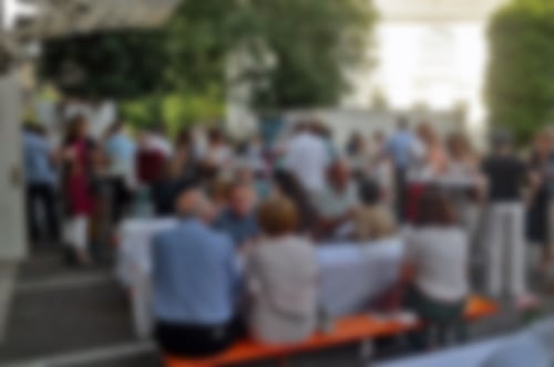 Veranstaltung an einem sonningen Tag. Menschen sitzen an Festzeltgarnituren