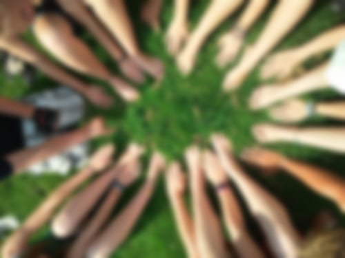 viele Hände und Füße bilden auf grünem Gras einen Kreis