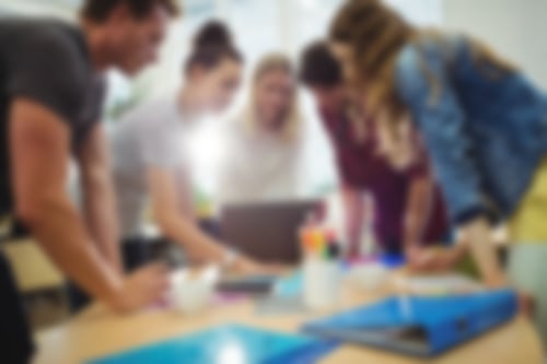 junge Menschen stehen um einen Tisch und besprechen ein Projekt