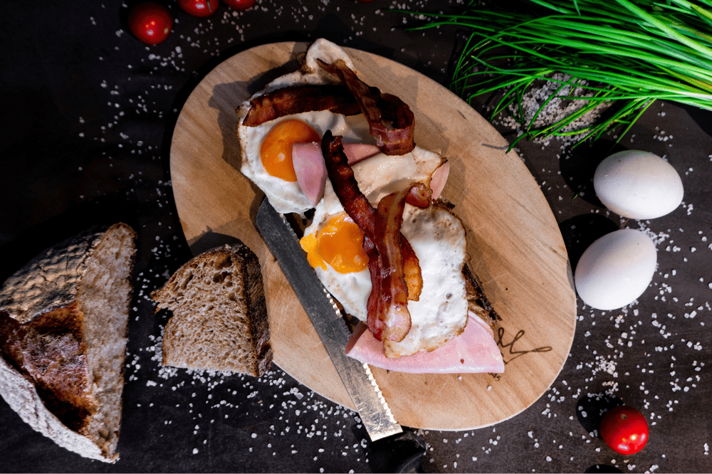 Frühstück mit belegtem Brot mit Spiegelei und Bacon von der Bäckerei Essmanns Backstube.