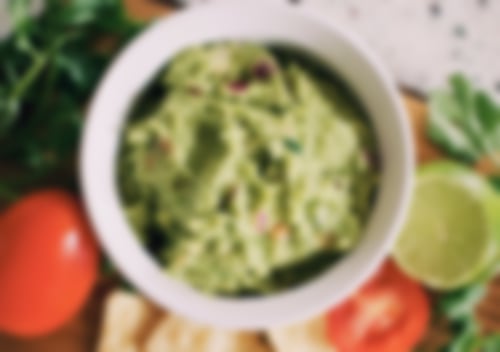 Cremige, selbstgemachte Guacamole mit Tomatenstückchen, Limette, Zwiebel und frischen Kräutern – veganer Brotaufstrich