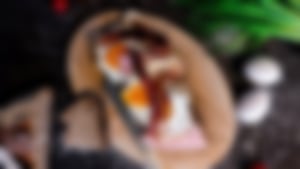 Belegtes Brot mit Spiegelei, knusprigem Bacon und Schinken, angerichtet auf einem Holzbrett mit Schnittlauch, Eiern und Brotscheiben daneben.