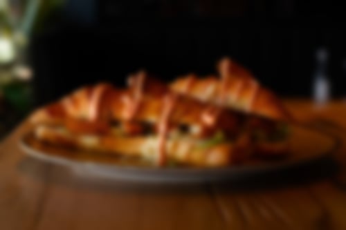 Knusprige Croissants, gefüllt mit panierten Fischstäbchen, frischem Eisbergsalat und garniert mit einer feinen Streifenhaube aus würziger Cocktailsauce.