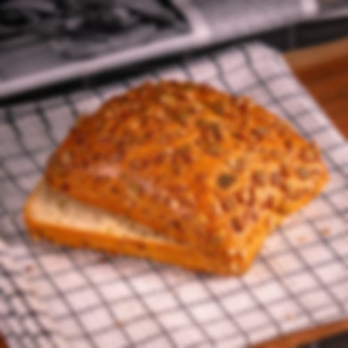 Herzhaftes Dinkelbrötchen mit goldbrauner Kruste, üppig bestreut mit gerösteten Kürbiskernen bei Essmann’s Backstube