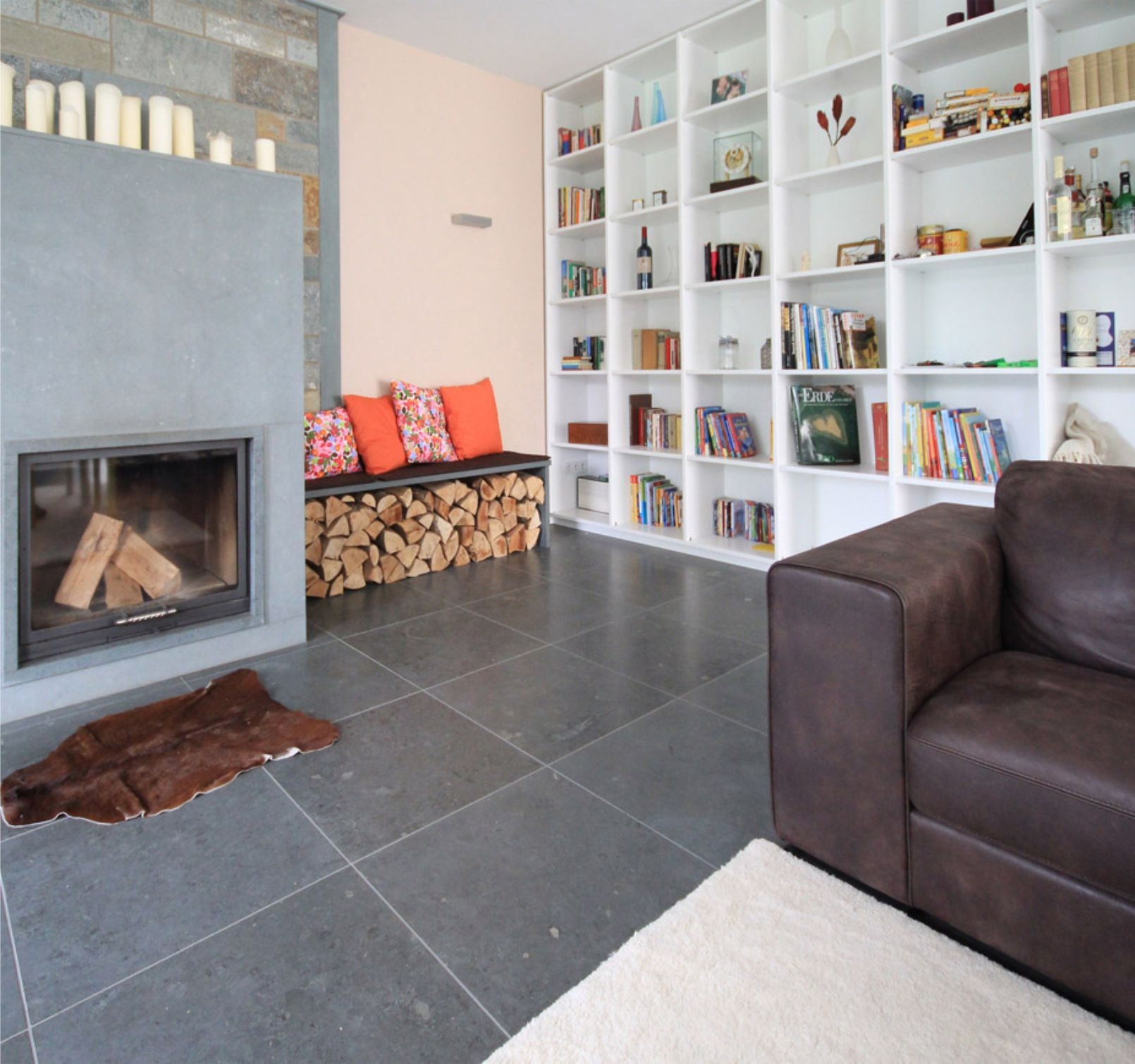 Wohnzimmer mit Kamin und Bücherregal und Natursteinfußboden