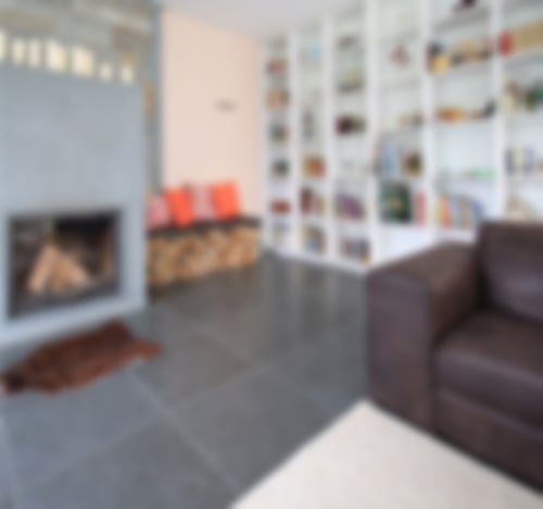 Wohnzimmer mit Kamin und Bücherregal und Natursteinfußboden