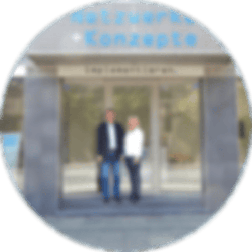 Kreis gefüllt mit dem Bild von Netzwerke + Konzepte - vor der Tür stehend die Inhaber Andre und Dagmar Schneider