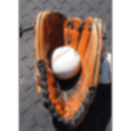 Ein Baseball, der in einem braunen Baseballhandschuh liegt.