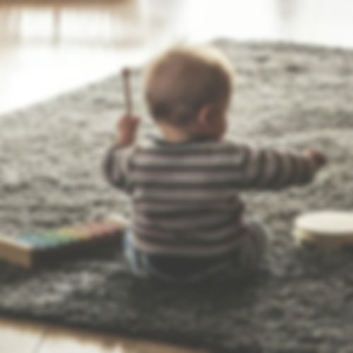 Kleinkind beim Spielen auf dem Teppichboden