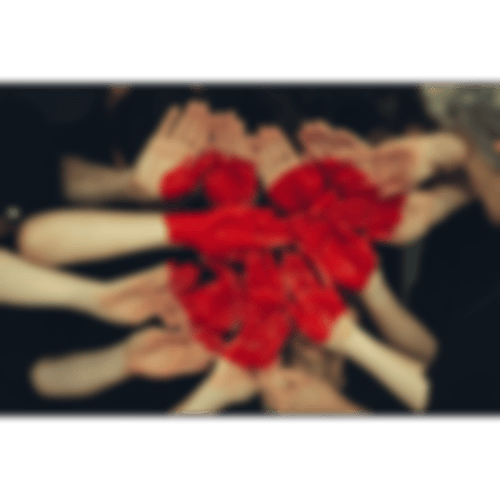 Viele Hände, die rot bemalt sind und ein Herz bilden.