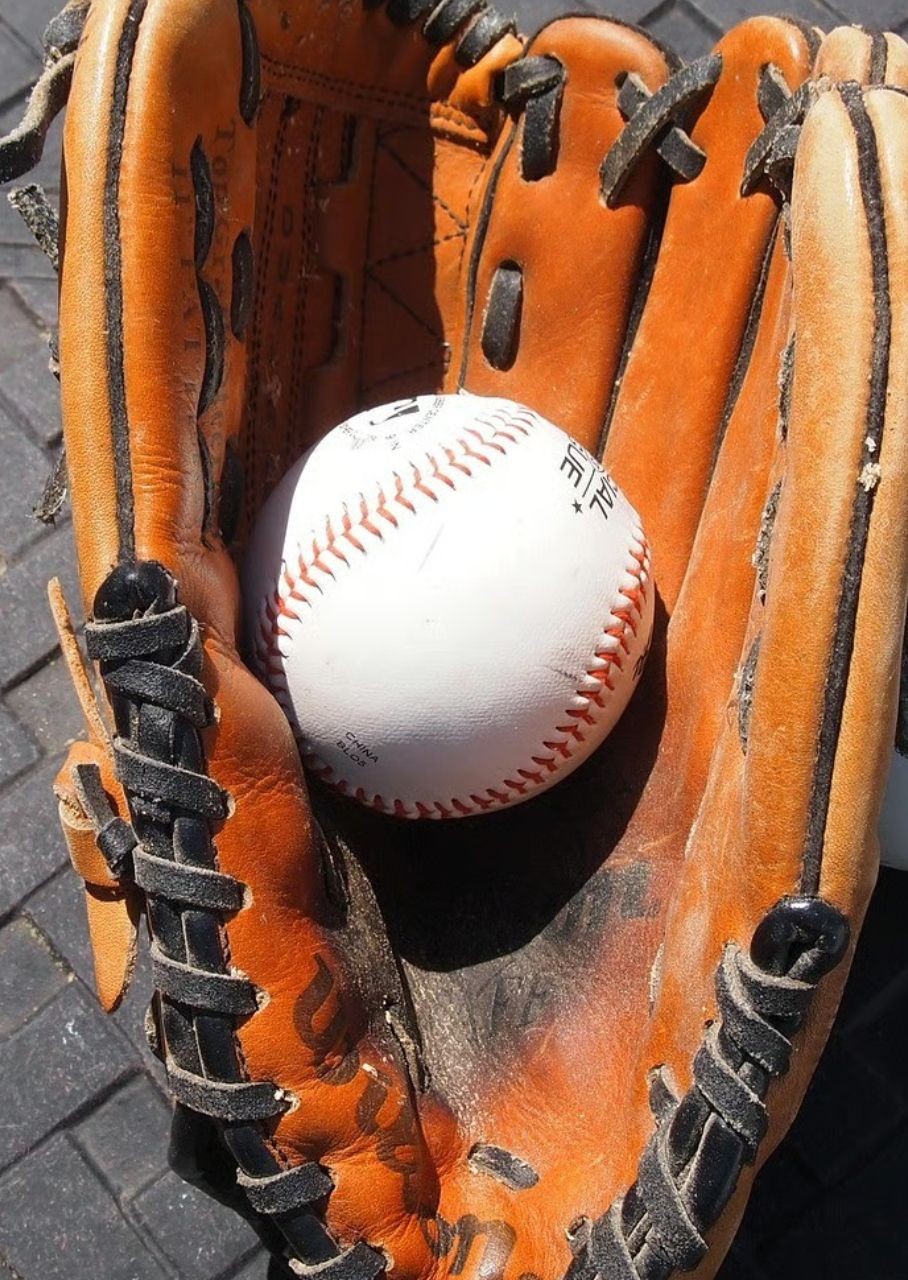 Ein Baseball, der in einem braunen Baseballhandschuh liegt.