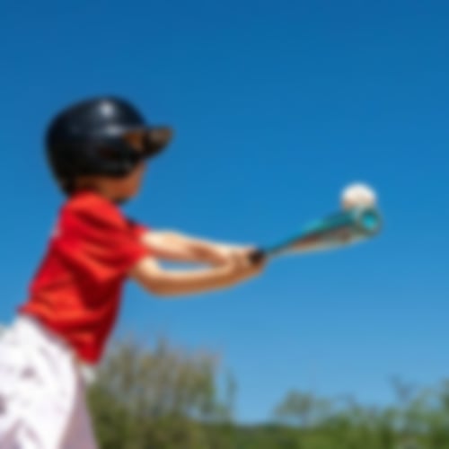 Kind in Baseballoutfit und Baseballschläger in der Hand, mit welchem er zum Schlag ausholt.