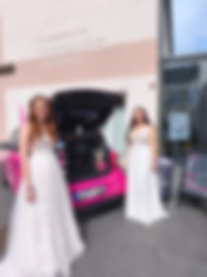 Zwei Frauen in Brautkleidern stehen bei der Hochzeitsmesse vor einem pinkfarbenen Kaffeemobil